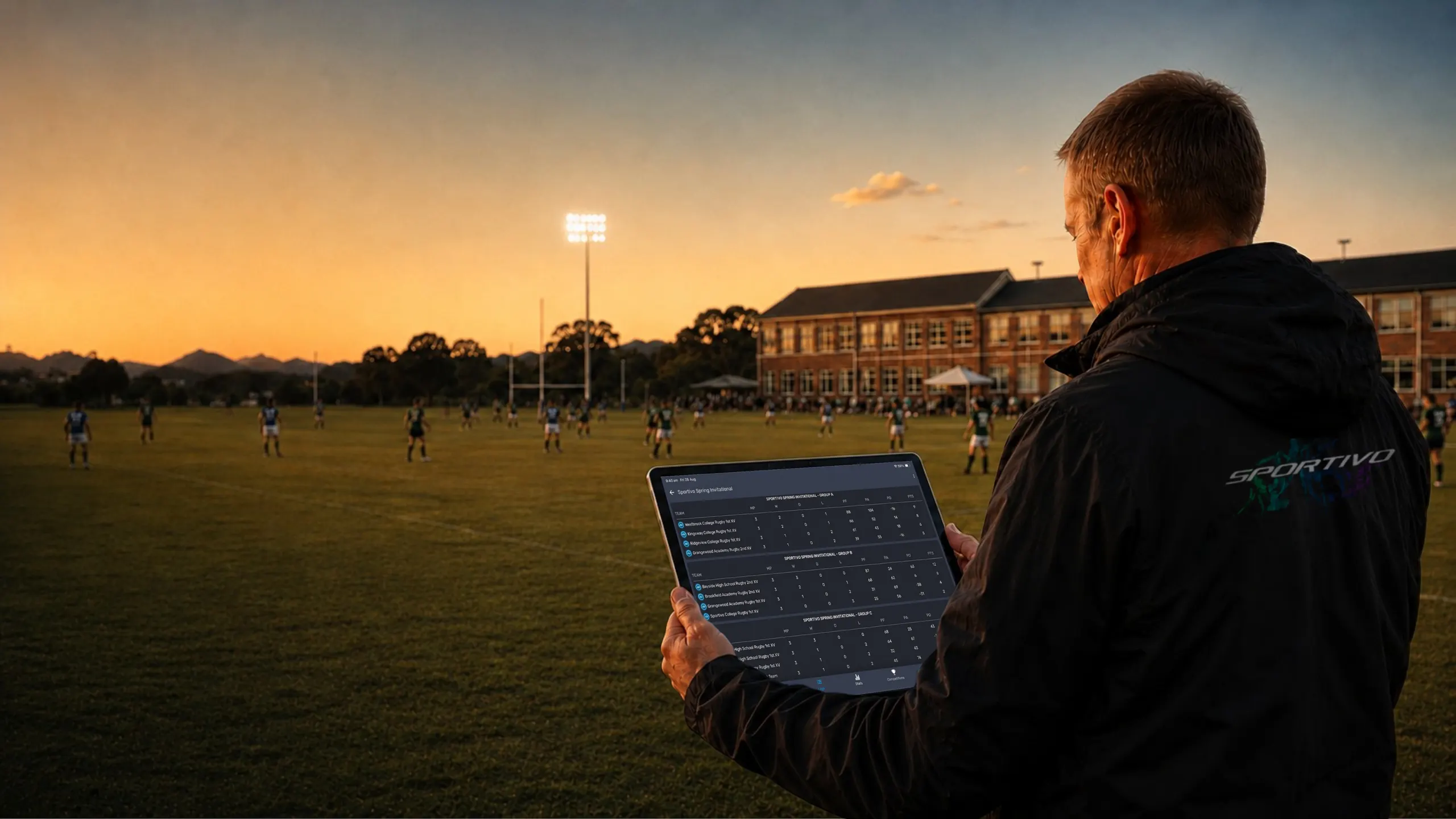 Tournament official checking section progress on a tablet beside a school rugby match